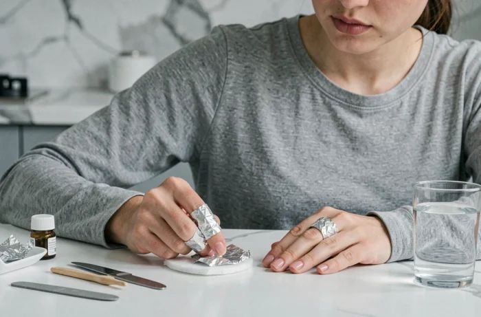 Femme utilisant la technique papier aluminium pour enlever la porcelaine de ses ongles à la maison